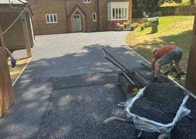 A contractor installing black resin bound driveway at a period property in the Bedfordshire countryside