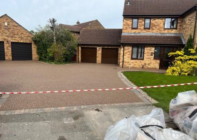 Spacious light brown resin bound driveway surrounded by brick houses.