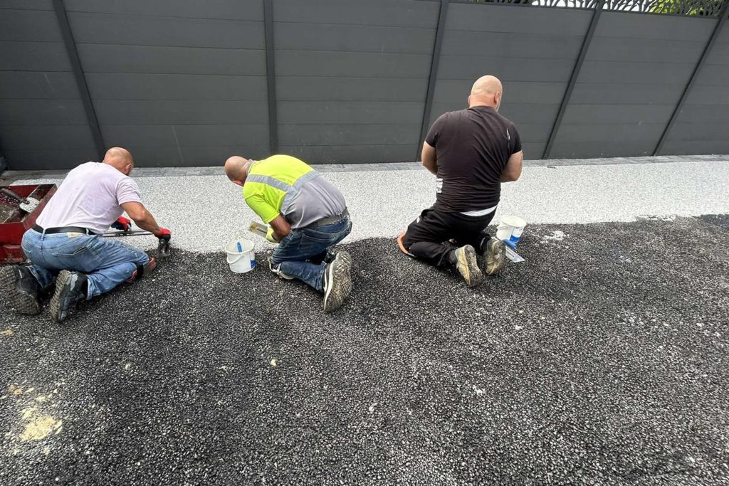 Three workers applying resin driveway surface