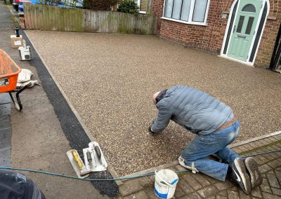 Worker applying resin on driveway
