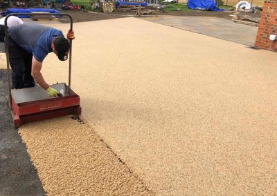 Worker applying resin driveway surface