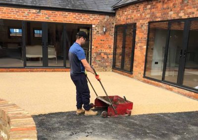 Worker applying resin driveway surface