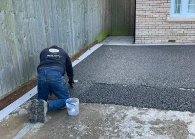Worker applying resin driveway surface