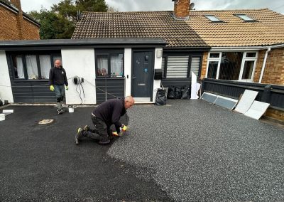 Worker applying resin on driveway