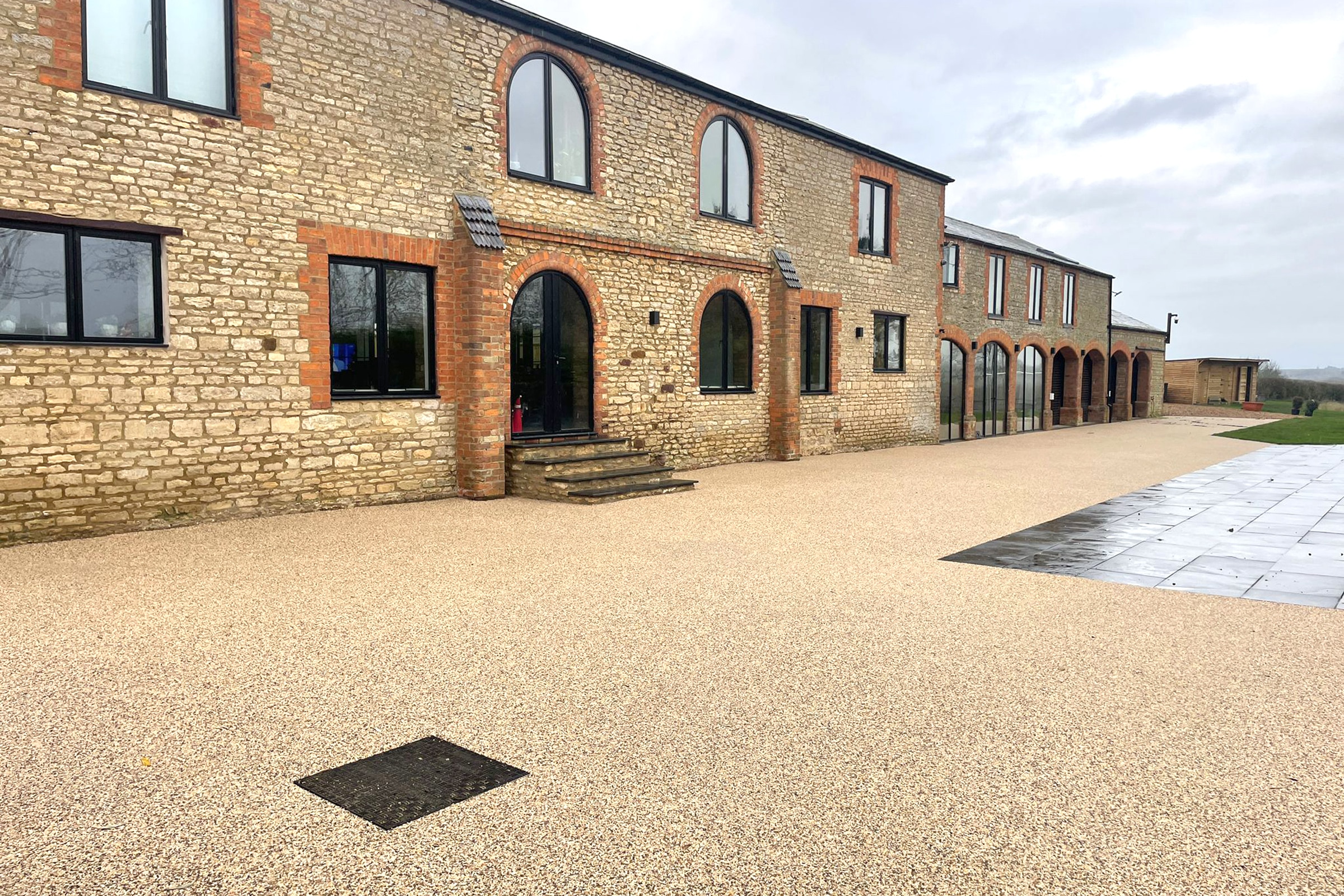 Large stone barn conversion with expansive light brown resin bound driveway.
