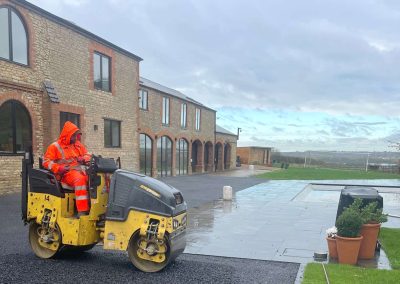 Worker operating roller on driveway
