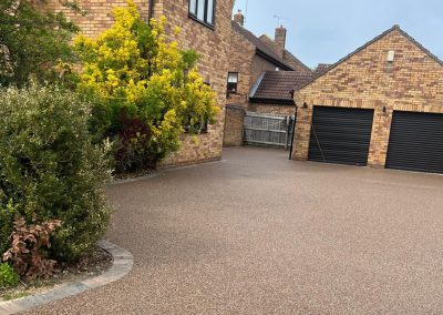 Spacious light brown resin bound driveway surrounded by brick houses.