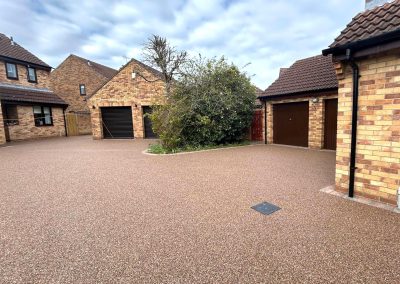 Spacious light brown resin bound driveway surrounded by brick houses.