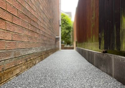 Narrow resin pathway between brick walls