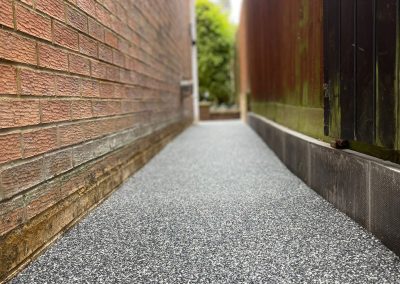 Narrow resin pathway between brick walls