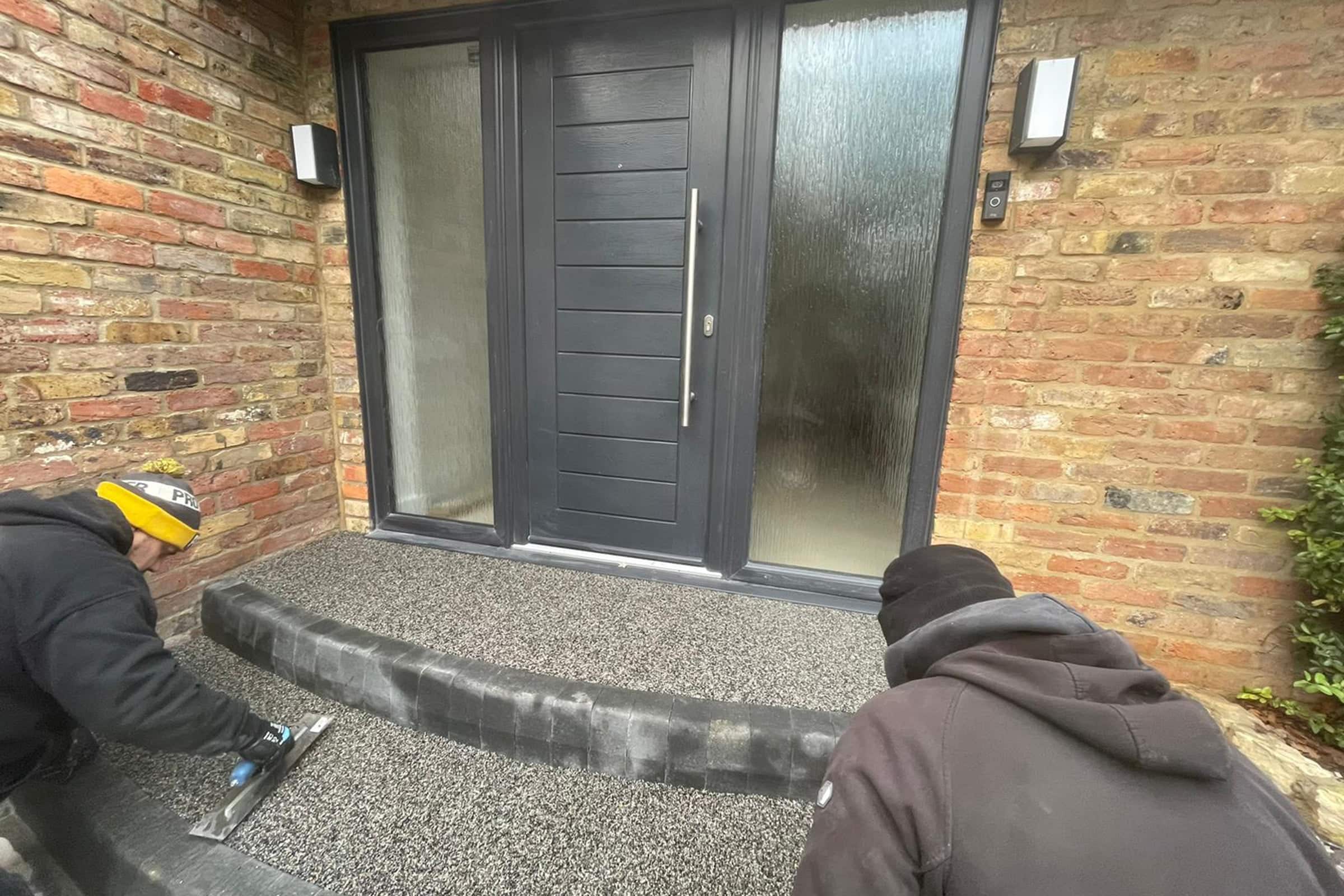 Workers installing resin bound steps at entrance to house